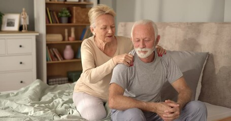 Elderly woman massaging her husband in bed - Powered by Adobe