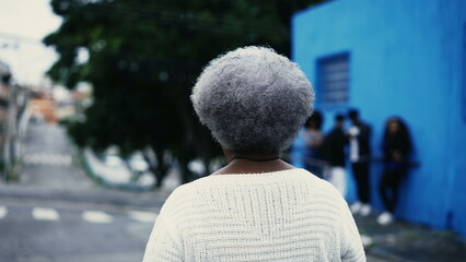 One pensive black senior woman strolling outdoors in city street with thoughtful gaze, close-up...