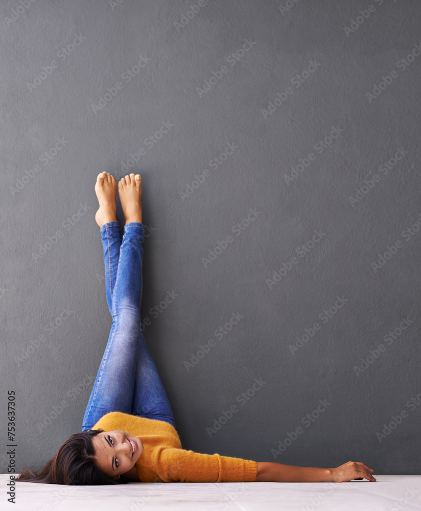 Sticker Portrait, floor and happy woman relax with casual style on a grey wall background for rest. Leisure, style and face of smiling female person upside down on a dark studio backdrop for fashion