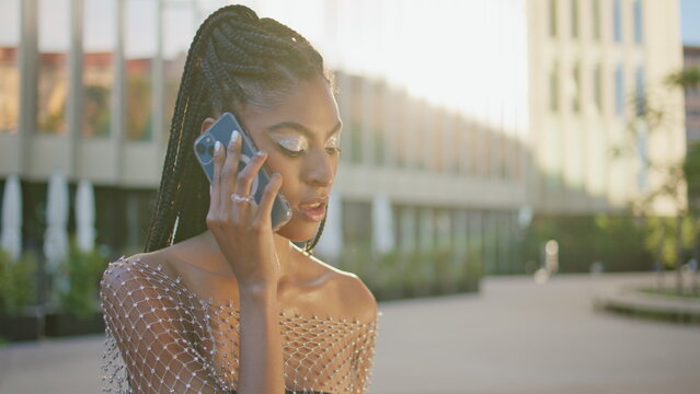 Dreamy african lady calling smartphone at sunny square closeup. Woman talking