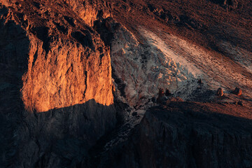 Dusk light paints a vivid contrast on a mountain face in Patagonia, Argentina, highlighting the intricate geological textures and formations