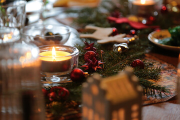 Weihnachtsdeko  und eine brennende Kerze auf einem Tisch 