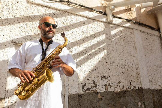 Musician playing saxophone in urban setting for Jazz Day