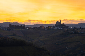 Serralunga d'Alba and its castle with vineyards at sunrise in backlight in autumn, Cuneo, Langhe and Roero, Piedmont, Italy