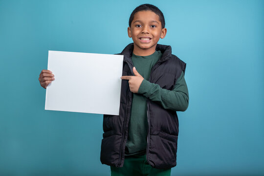 Elementery School Hispanic Boy Looking At The Camera Holding A Sign