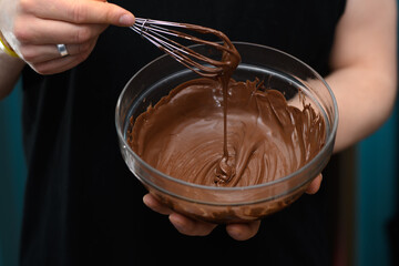 Miska z płynną błyszcząca polewą czekoladową z bliska w dłoniach 