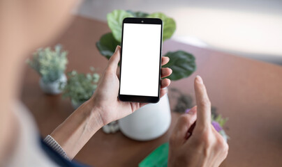 Simulated image of a blank white screen mobile phone Woman using mobile phone on table at home