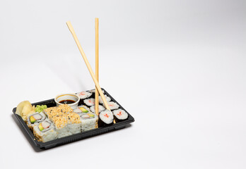 Sushi to go in a black takeaway box with wooden chopsticks on white background 