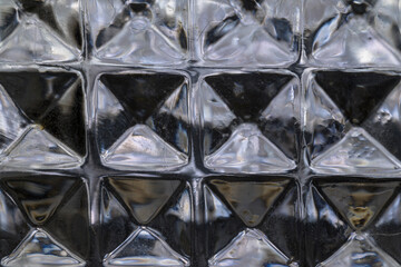 Detail of glass liquor bottle cut square hexagons illuminated in dark horizontal