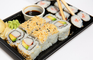 Close up of sushi to go in a black takeaway box with wooden chopsticks on white background 