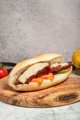 Turkish bread sandwich with kashar sausage on the presentation board. Sausage in bread prepared with tomatoes, peppers and meatballs. Local name ekmek arası sucuk