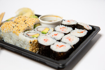 Sushi to go in a black takeaway box with wooden chopsticks on white background 