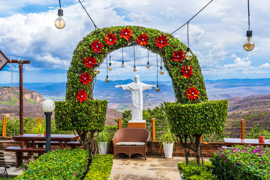 Miniature statue of Christ he Redeemer under a floral arch in a brazilian garden