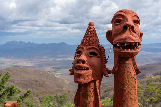 Close-up on faces of traditional brazilian statues sculpted in clay against a natural landscape