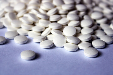 A lot of white pills are scattered on a white background.