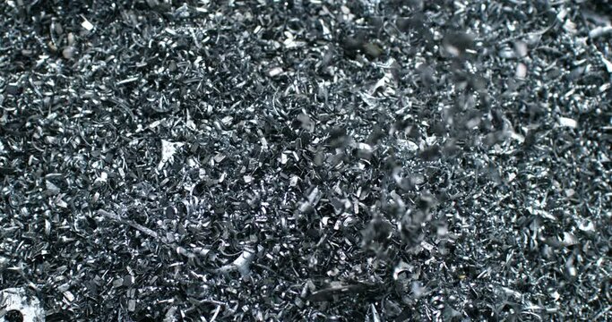 Super slow motion close up of falling scrap steel metal shavings during quality control sorting process at waste recycling plant of scrapyard of industrial factory. Recyclable reuse scrap metal waste.