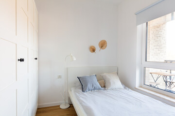Minimalist bedroom with white bedding, wardrobe and natural light