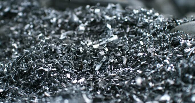 Super slow motion macro of falling scrap steel metal shavings during quality control sorting process at waste recycling plant of scrapyard of industrial factory. Recyclable reuse scrap metal waste.