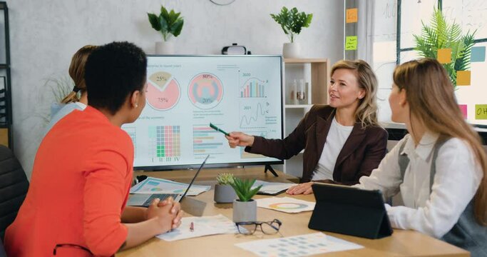 Smiling international woman team which discussing joint business concept and putting their palms together making partnership sign during meeting