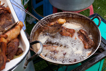 Photograph of pork frying in hot oil to prepare Peruvian chicharron. Peruvian food concept.