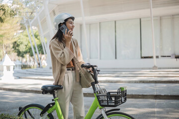 Young businesswoman parks his bicycle and talks on the phone in the park.