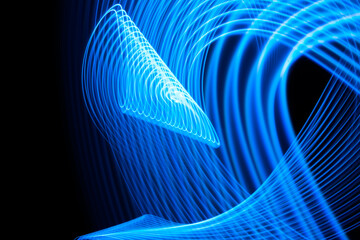 Long exposure light painting curvy lines of vibrant neon metallic blue on black background. High quality photo