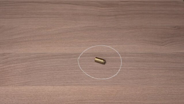 Crime Scene Investigation - forensic officer marks a bullet casing using white chalk and places a yellow marker nearby