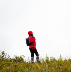 Explorando el invierno Chica con mochila y chompa rojo disfrutando del paisaje campestre bajo un cielo nublado,turista viajero,estilo de vida