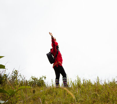 Explorando el invierno Chica con mochila y chompa rojo disfrutando del paisaje campestre bajo un cielo nublado,turista viajero,estilo de vida