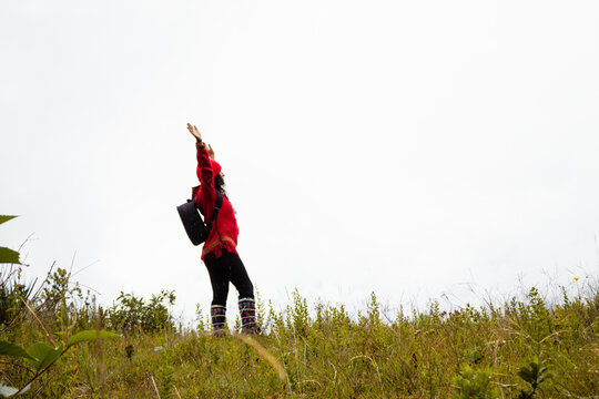 Explorando el invierno Chica con mochila y chompa rojo disfrutando del paisaje campestre bajo un cielo nublado,turista viajero,estilo de vida
