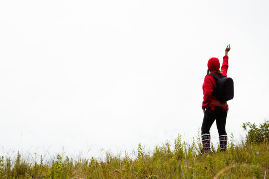 Explorando el invierno Chica con mochila y chompa rojo disfrutando del paisaje campestre bajo un cielo nublado,turista viajero,estilo de vida
