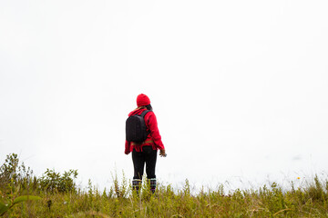 Explorando el invierno Chica con mochila y chompa rojo disfrutando del paisaje campestre bajo un cielo nublado,turista viajero,estilo de vida