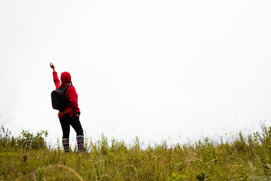 Explorando el invierno Chica con mochila y chompa rojo disfrutando del paisaje campestre bajo un cielo nublado,turista viajero,estilo de vida