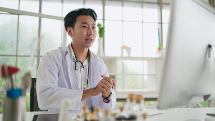 Fototapeta na wymiar Online medical consultation. Young asian male doctor talking online with patient, making video call for helping consultation to treat illnesses. Medical and technology