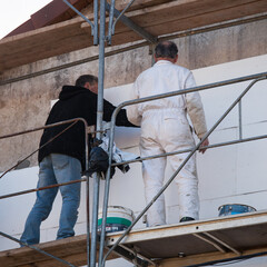 Deux ouvriers sur un échafaudage posent des panneaux isolants
