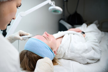 Close up of ultrasound skin cleaning and facial peeling procedure in beauty clinic. Macro shot of...