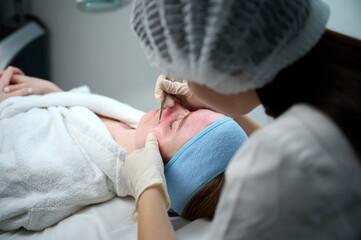 Close up of ultrasound skin cleaning and facial peeling procedure in beauty clinic. Macro shot of...