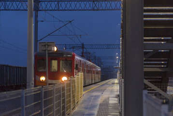 Elektryczny pociąg pasażerski na peronie dworcowym po zmroku.Oświetlony pociąg stojący na peronie w deszczowy styczniowy wieczór.