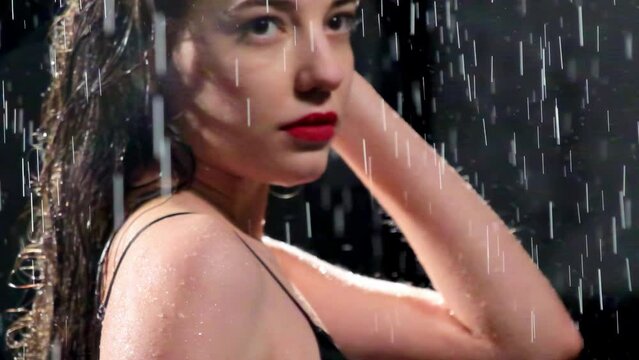 Attractive lady with red lipstick sits under cold downpour and peers into darkness. Elegant woman with strict sight gets angry about bad weather
