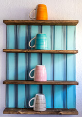 Tassen in einem Regal an der Wand vertikal angeordnet