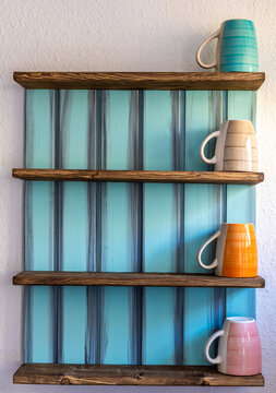 Tassen in einem Regal an der Wand vertikal angeordnet
