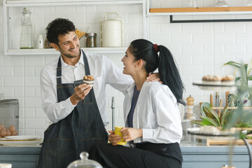Beautiful happy cheerful caucasian couple wear apron in kitchen and dessert breakfast morning with love emotion. man and women lover chef.