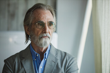 Portrait of senior handsome man wear eyeglasses with grey hair and beard arms crossed look out...