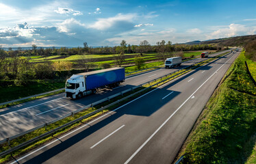Highway transport. Transportation Trucks in lines passing on a rural countryside highway under a...