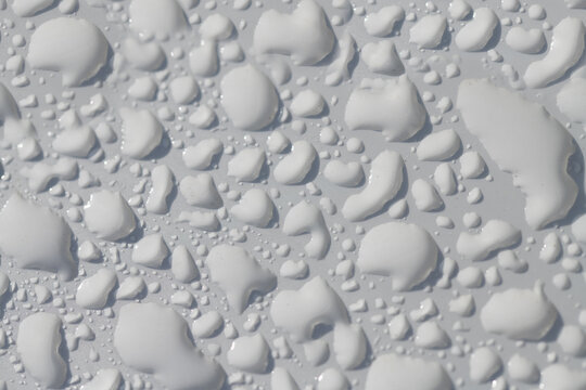 Close-up, background and close-up of a white lacquered surface on which many water pearls shimmer.