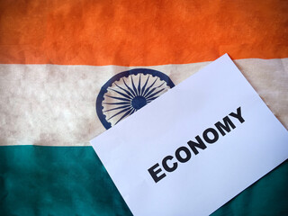 Economy text in paper with Indian Flag in background. Indian Economy Concept. 