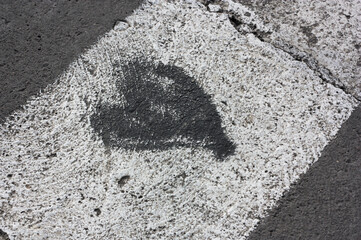 A black heart on a pedestrian crossing in a city