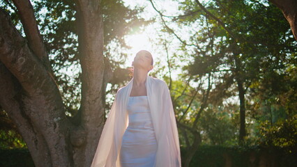 Silhouette woman posing sunlight in white clothes. Model standing sunny park