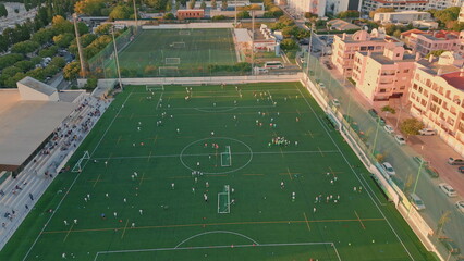 Beautiful village football stadium at summer evening aerial. Green soccer field 