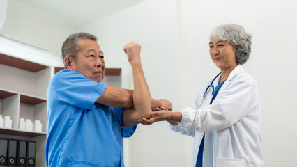 An elderly Asian man is doing physical therapy with the support of an elderly female nurse using dumbbells and tubes to exercise for a patient.